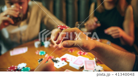 Side view photo of friends sitting at wooden table. Friends having fun while playing board game. 41340048