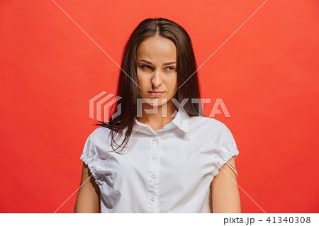 The serious business woman standing and looking at camera against red background. 41340308