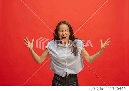 The young emotional angry woman screaming on red studio background 41340462