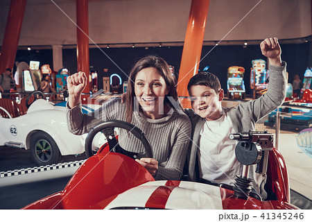 Happy smiling mother and son sitting on toy car Happy smiling mother and son sitting on toy car 41345246