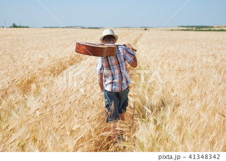 child boy with guitar is in the yellow wheat field 41348342