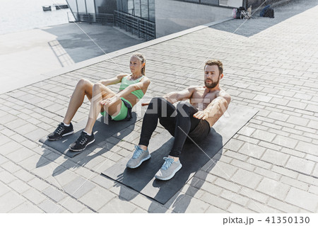 Fit fitness woman and man doing fitness exercises outdoors at city 41350130