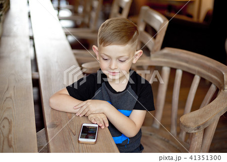 little boy with smartphone sitting at the table 41351300