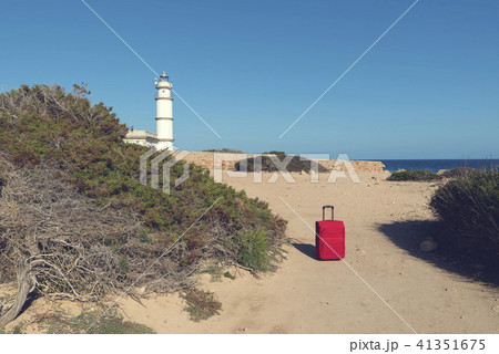 Red suitcase on a path to lighthouse  41351675