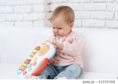 Smiling newborn baby on sofa playing toy. Smiling newborn baby on sofa playing toy. 41352408