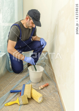 Painter paints the wall with the tint of white. 41358616