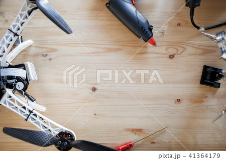 Image of broken quadrocopter on table with soldering iron, glue gun 41364179