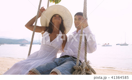 Young happy pretty couple on a swing at the tropical beach against the sea 41364585