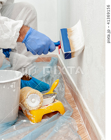 House painter at work painting a wall with a brush House painter at work painting a wall with a brush 41369156