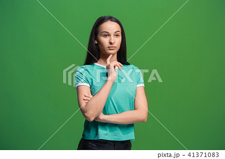 Let me think. Doubtful pensive woman with thoughtful expression making choice against grreen 41371083