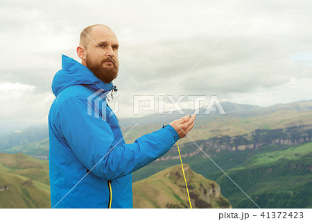 Hipster man in a blue jacket using a compass on the background in the background of the Caucasian 41372423