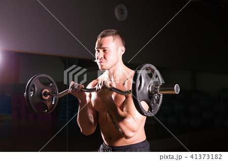 Handsome power athletic man with barbell. Strong bodybuilder with six pack, perfect abs, shoulders 41373182