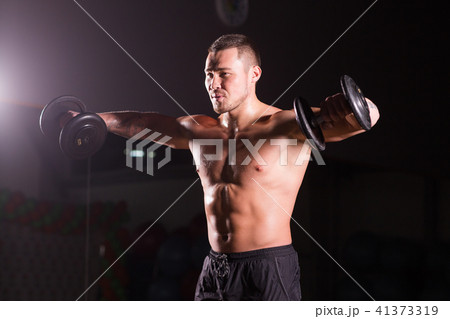Handsome power athletic man with dumbbell. Strong bodybuilder with six pack, perfect abs, shoulders 41373319