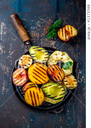 GRILLED FRUITS. Grill fruits - pineapple, peaches, plums, avocado, pear on black cast iron grill pan GRILLED FRUITS. Grill fruits - pineapple, peaches, plums, avocado, pear on black cast iron grill pan 41373566