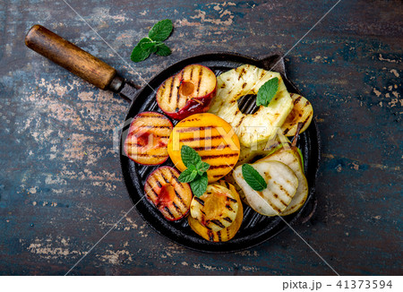 GRILLED FRUITS. Grill fruits - pineapple, peaches, plums, avocado, pear on black cast iron grill pan GRILLED FRUITS. Grill fruits - pineapple, peaches, plums, avocado, pear on black cast iron grill pan 41373594