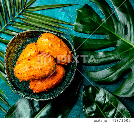 Tropical fruin KIWANO passion fruit in green bowl on turquoise background with tropical palm tree Tropical fruin KIWANO passion fruit in green bowl on turquoise background with tropical palm tree 41373609