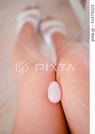 Rose quartz yoni egg between woman's legs 41375023