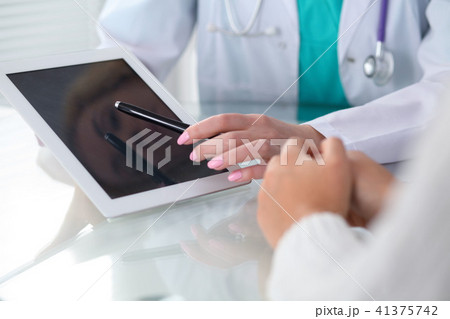 Doctor and patient, close-up.  Physician pointing into touch pad screen of tablet computer. Medicin 41375742