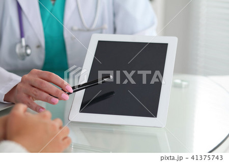 Doctor and patient, close-up. Physician pointing into touch pad screen of tablet computer. Medicin Doctor and patient, close-up. Physician pointing into touch pad screen of tablet computer. Medicin 41375743