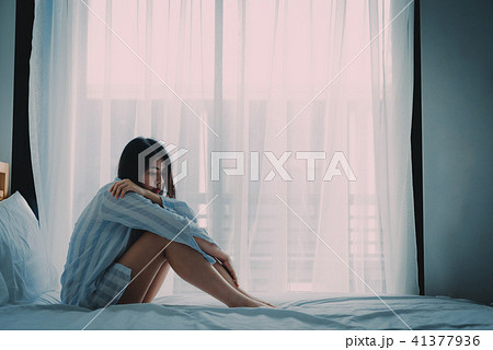 woman sitting on a bed looking sad and lonely 41377936