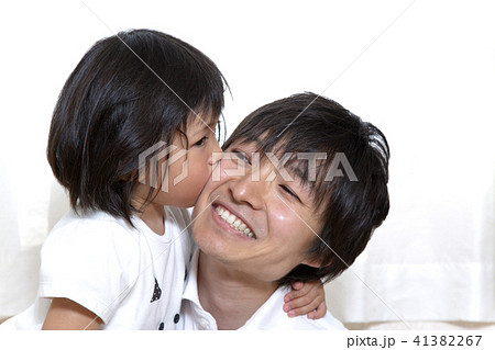 幼い娘にキスされる父親 幸せな家族シーンの写真素材