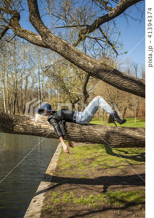 Fashion woman lying on a tree in park Fashion woman lying on a tree in park 41394374