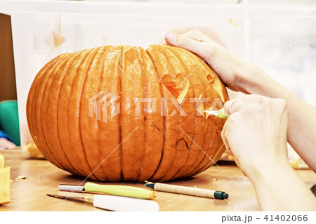 Women's hands who cuts jack-o-lantern with knife Women's hands who cuts jack-o-lantern with knife 41402066