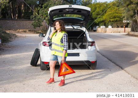 Broken down car with warning triangle. Woman standing alongside her broken down car on the road and 41413031