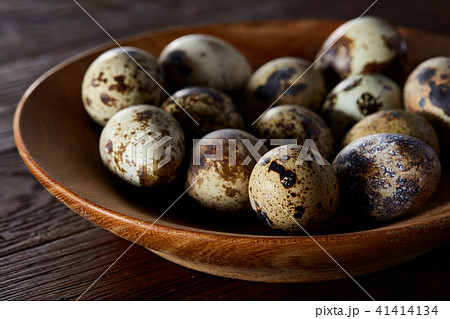 Fresh quail eggs in a wooden bowl on a dark wooden background, top view, close-up Fresh quail eggs in a wooden bowl on a dark wooden background, top view, close-up 41414134