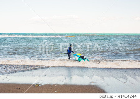 Man carrying his kayak along the shore. 41414244
