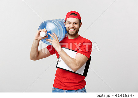 Handsome young delivery worker in red uniform is holding a bottle of water, looking at camera and Handsome young delivery worker in red uniform is holding a bottle of water, looking at camera and 41416347