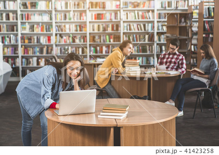 Optimistic lady working with gadget in library Optimistic lady working with gadget in library 41423258