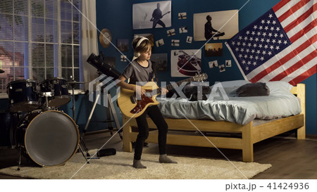 Expressive youngster playing guitar in bedroom Expressive youngster playing guitar in bedroom 41424936