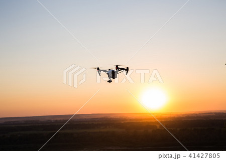 silhouette of drone, quadrocopter with photo camera flying in the sky. silhouette of drone, quadrocopter with photo camera flying in the sky. 41427805