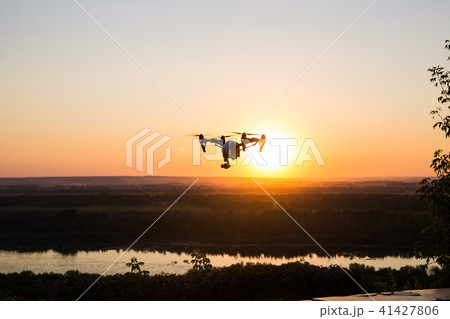silhouette of drone, quadrocopter with photo camera flying in the sky. silhouette of drone, quadrocopter with photo camera flying in the sky. 41427806