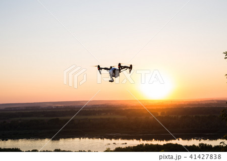 silhouette of drone, quadrocopter with photo camera flying in the sky. 41427838