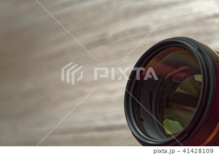 Camera lens with reflections on wooden background Camera lens with reflections on wooden background 41428109
