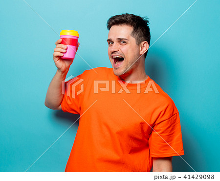 man in orange t-shirt with cup of coffee man in orange t-shirt with cup of coffee 41429098