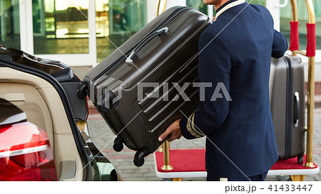 Bellboy taking baggage of guest from thee car to his room 41433447