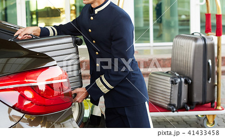 Bellboy taking baggage of guest from thee car to his room Bellboy taking baggage of guest from thee car to his room 41433458