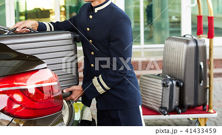 Bellboy taking baggage of guest from thee car to his room Bellboy taking baggage of guest from thee car to his room 41433459