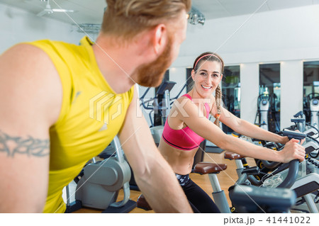 Woman smiling at the handsome man next to her while cycling at the gym 41441022
