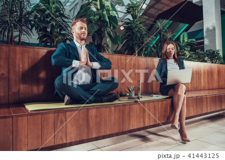 Worker meditating on bench in office. Worker meditating on bench in office. 41443125