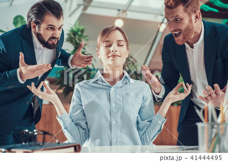 People shout at meditating worker in office. 41444495