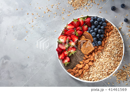 Fresh berries, almonds, oatmeal and granola in a plate with gray concrete background top view 41461569