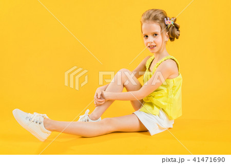 A teenage girl is sitting on a yellow background. A teenage girl is sitting on a yellow background. 41471690