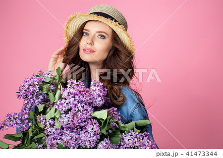 Happy smiling woman enjoying smell of bouquet lilac flowers over 41473344