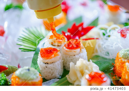 A lot of sushi rolls with different fillings. Shot of cooked classic Japanese food served on ice A lot of sushi rolls with different fillings. Shot of cooked classic Japanese food served on ice 41473403