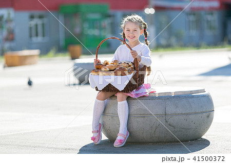 Little girl with a basket of bread. 41500372