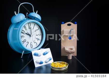 Toilet paper, capsules and alarm clock on black Toilet paper, capsules and alarm clock on black 41503164